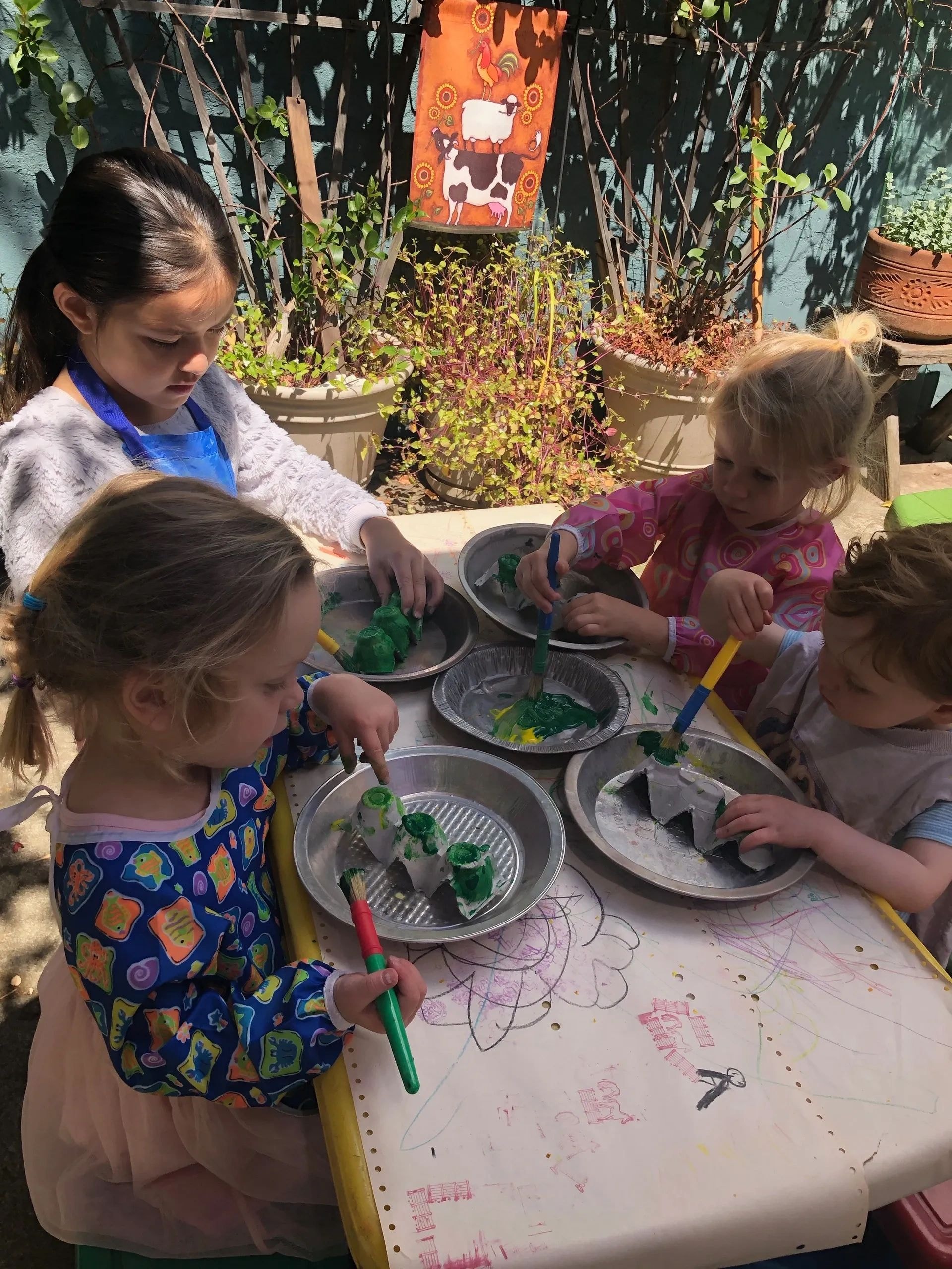 Children painting together outdoors in the garden