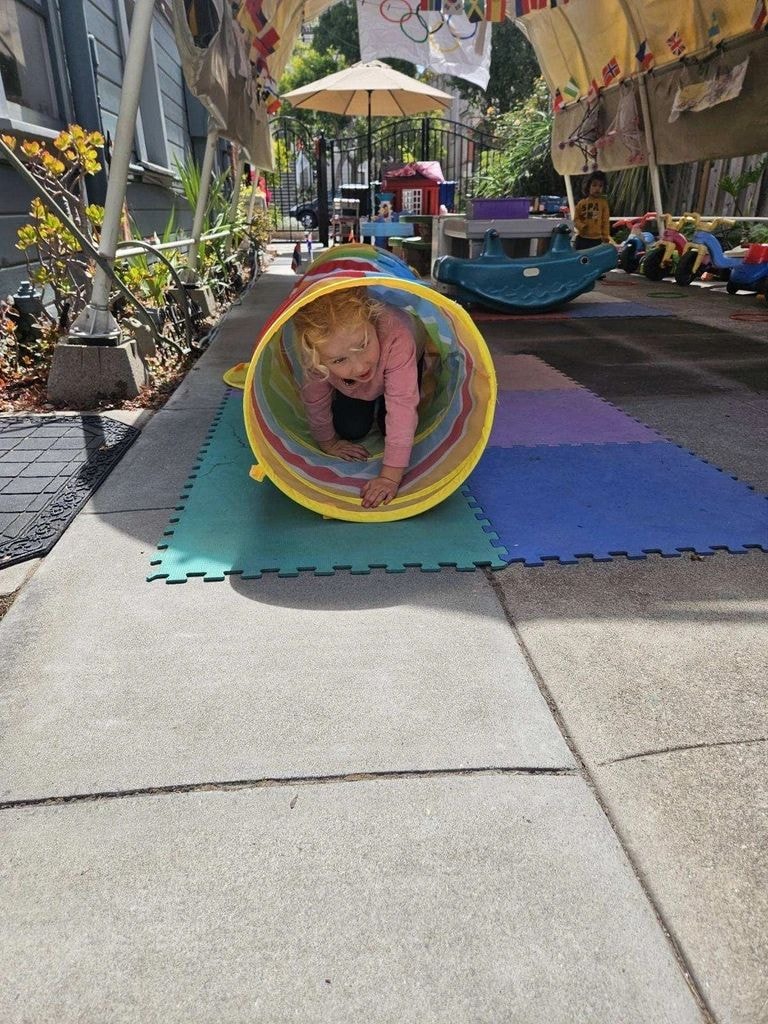 Child crawling through colorful play tunnel
